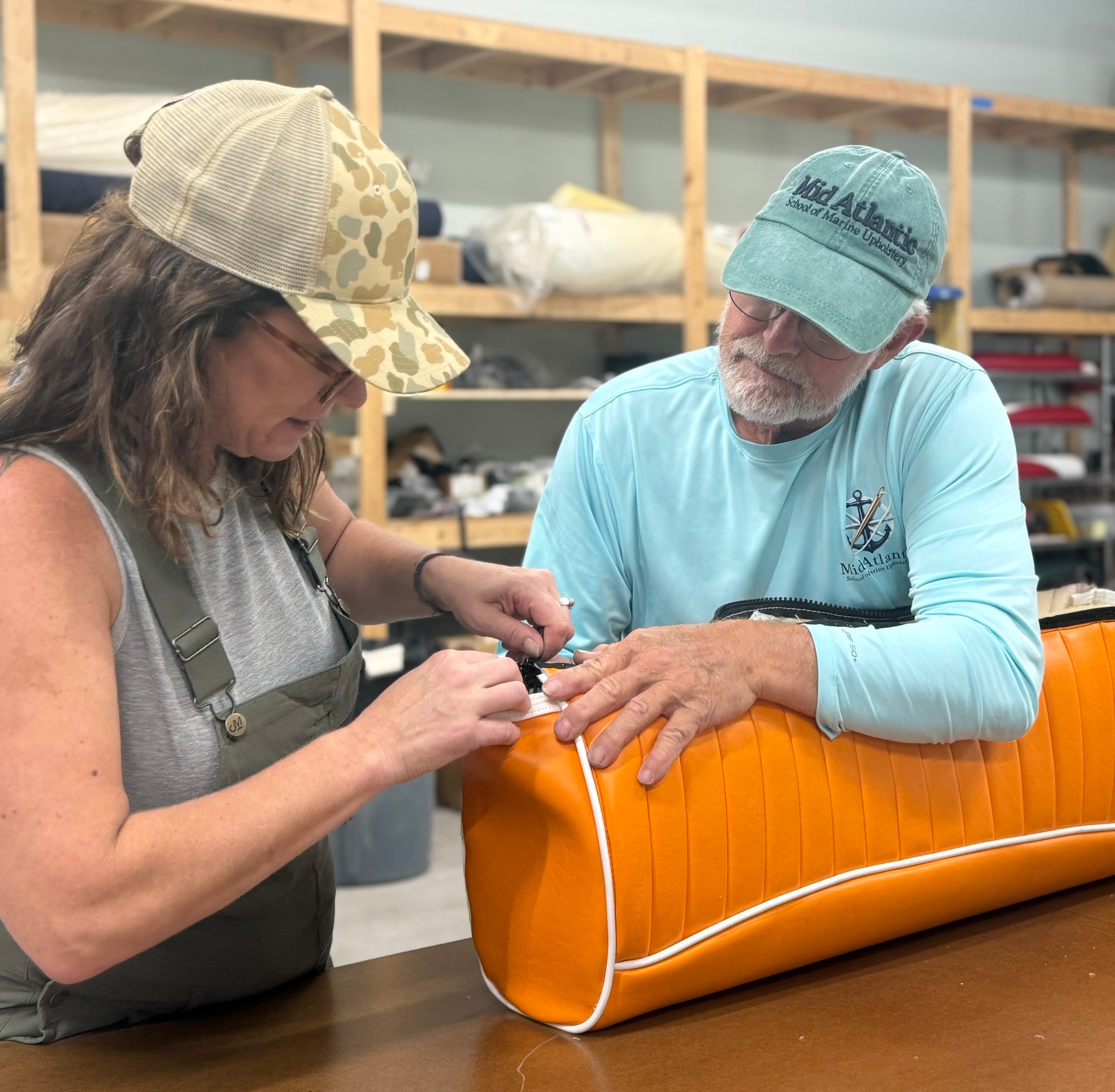 Students working with orange boat model at Mid Atlantic School of Marine Upholstery
