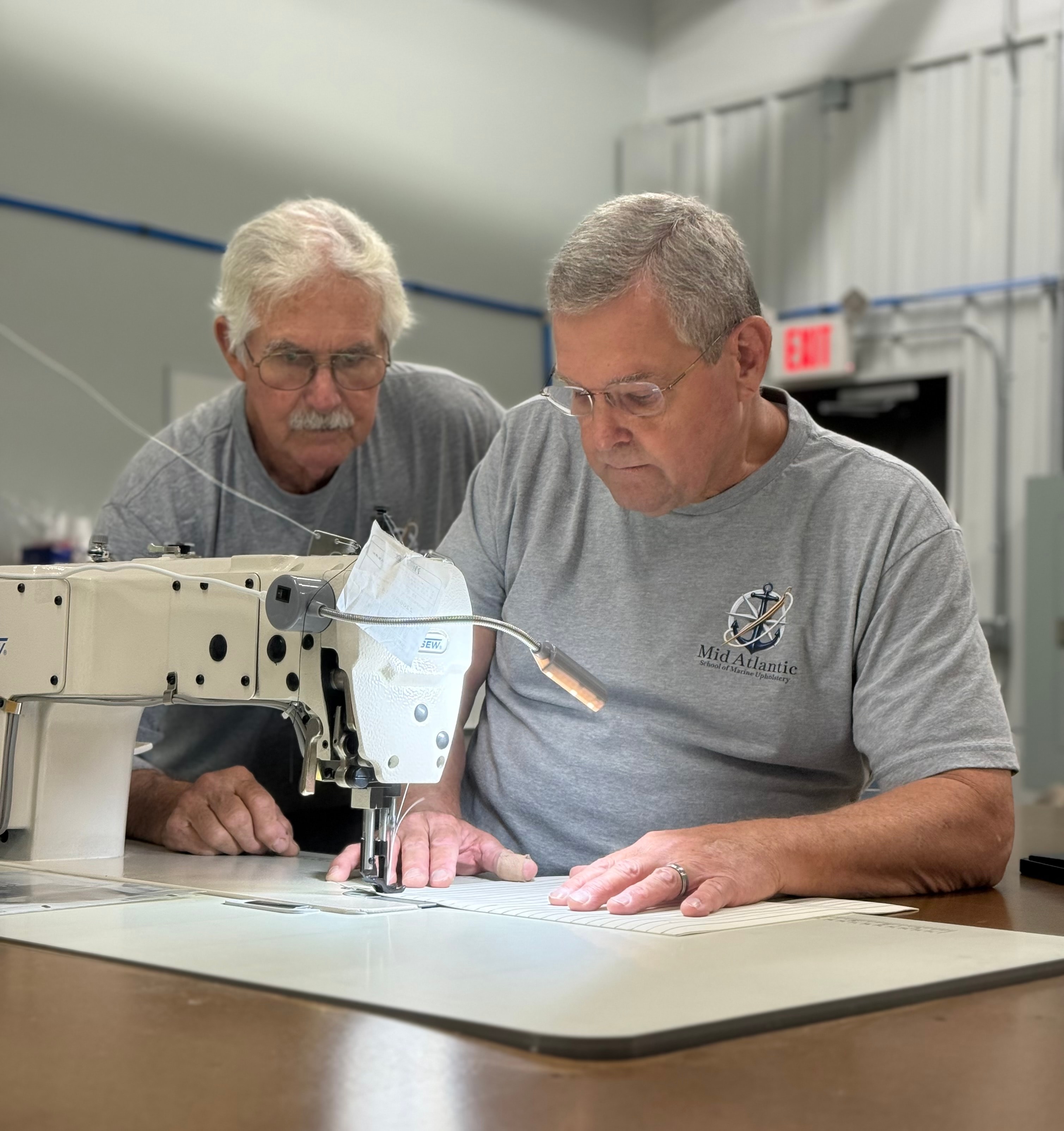 Instructor teaching student on industrial sewing machine at Mid Atlantic School of Marine Upholstery