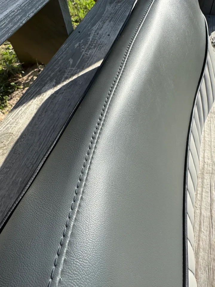Close-up of charcoal gray marine vinyl with precision saddle stitching seam detail