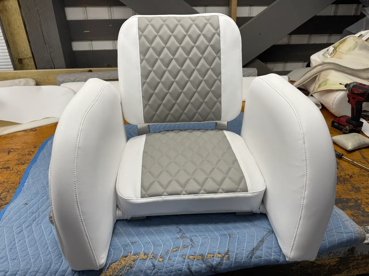 White and gray diamond-quilted captain chair with armrests on workshop bench