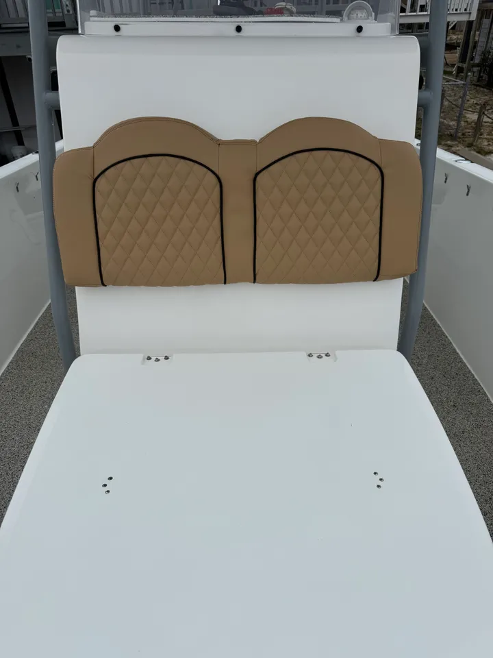Tan diamond-quilted double seat back with black piping mounted on white boat at marina